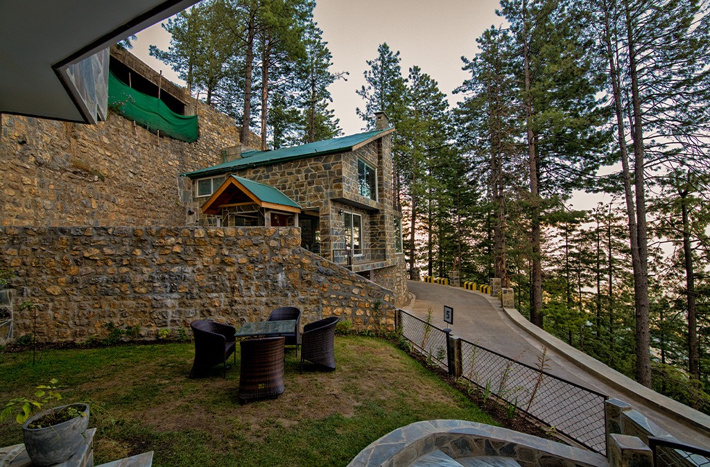 Stone villa exterior with garden seating area and pine forest view — Blue Pine Mountain Homes Galiyat