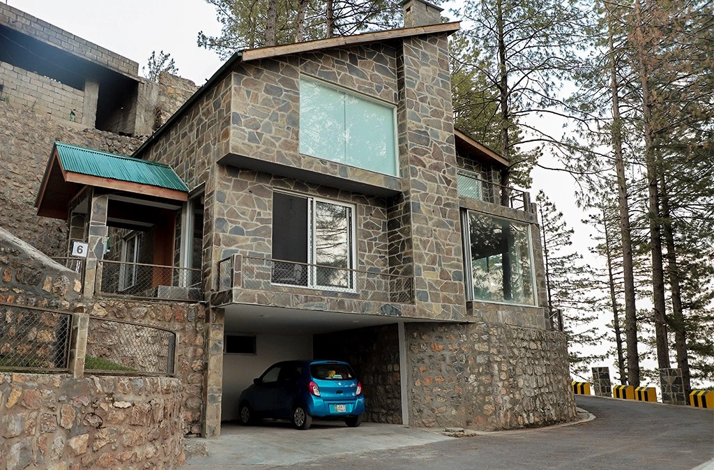 Stone-clad luxury villa with covered garage and pine trees — second home investment property in Galiyat Pakistan
