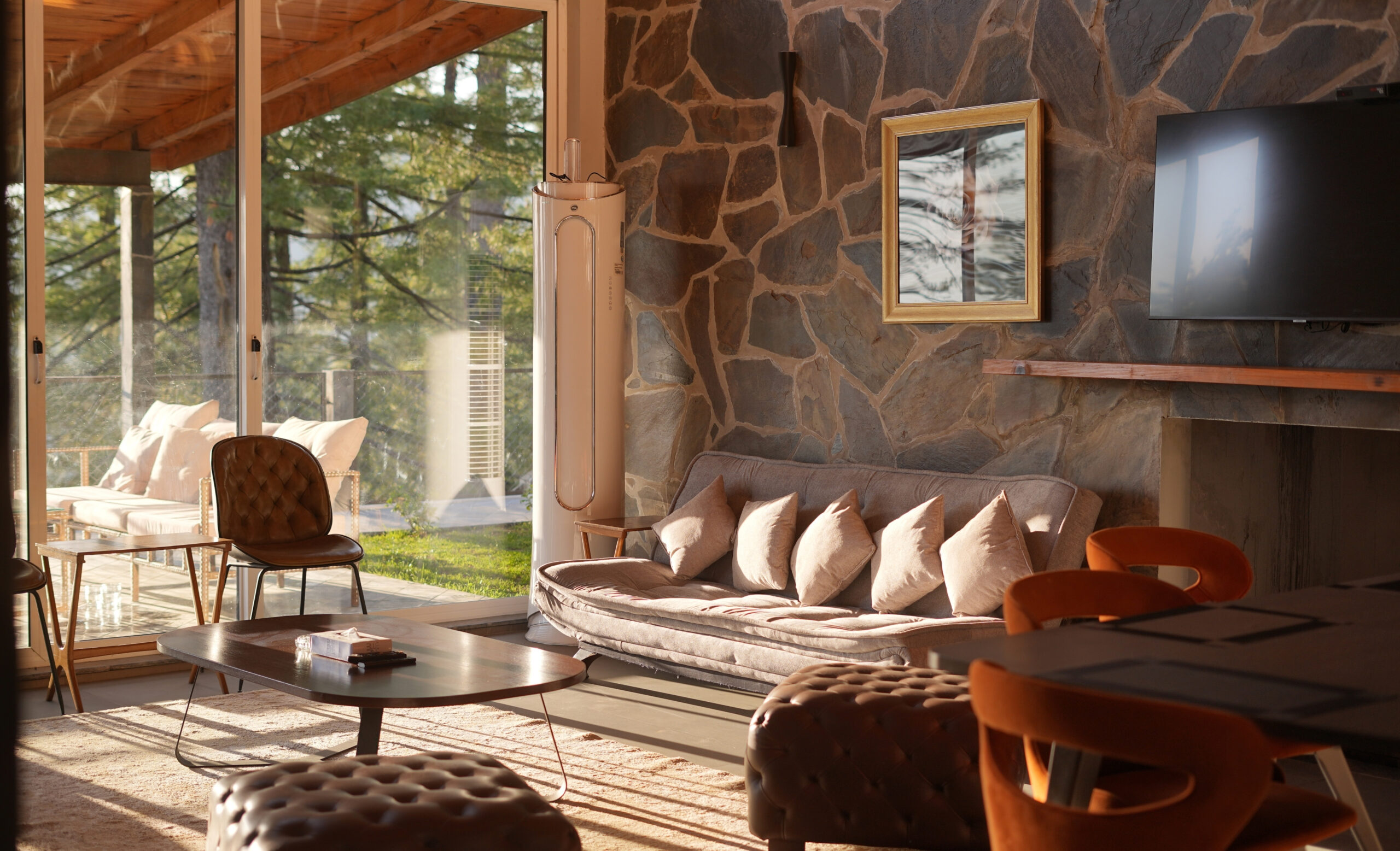 Best real estate investment in Pakistan — luxury living room interior with stone wall and pine forest view in a Galiyat mountain villa