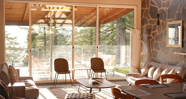 Sunlit living room overlooking pine forest, holiday homes in Pakistan mountains by Blue Pine Mountain Homes